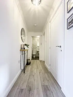 a hallway with white walls and wood floors and a chandelier at Pier View Apartment in Oban
