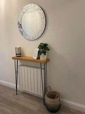 a mirror on a wall next to a table with a plant at Pier View Apartment in Oban