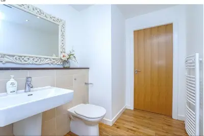 a bathroom with a sink and a toilet and a mirror at Oswald Apartment - Glasgow City Centre in Glasgow