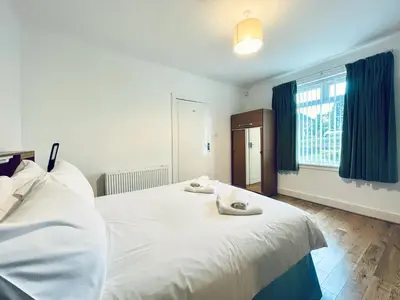 a bedroom with a large white bed and a window at Millerston House in Glasgow