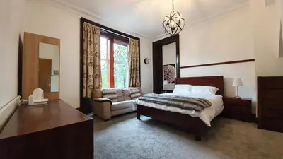 a bedroom with a bed and a chair and a window at Bemersyde Guest House in Mansewood