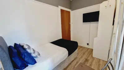 a small room with a bed with blue pillows on it at Bemersyde Guest House in Mansewood