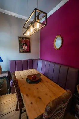 a dining room with a wooden table and pink wall at Traditional apt close to city centre & Hampden in Glasgow