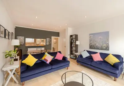 a living room with two blue couches with colorful pillows at The Old Bakery in Edinburgh
