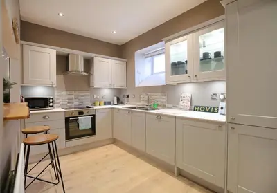 a kitchen with white cabinets and a stool in it at The Old Bakery in Edinburgh