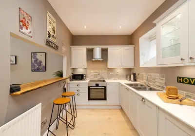 a kitchen with white cabinets and bar stools at The Old Bakery in Edinburgh