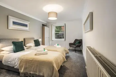 a bedroom with two beds and a chair at Renfrew Residence Central Glasgow 4-Bed Flat in Glasgow