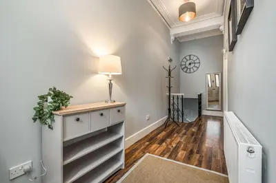 a hallway with white walls and a table with a lamp at Renfrew Residence Central Glasgow 4-Bed Flat in Glasgow