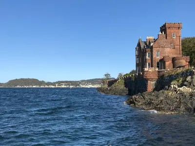 an old building on the shore of a body of water at Kilbowie Retreat in Oban
