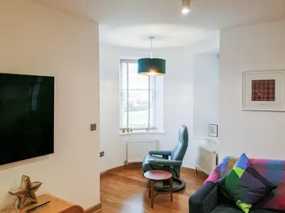 a living room with a couch and a chair at Kilbowie Retreat in Oban