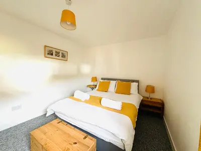a bedroom with a large white bed with yellow pillows at Tillicoultry Jupiter Apartment - Scotland Holiday Let in Tillicoultry