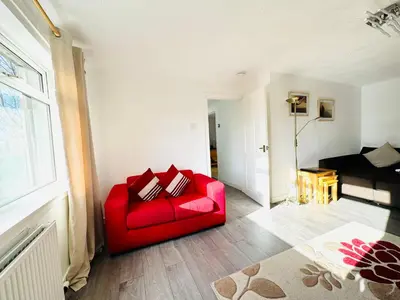 a red couch in a living room with a window at Tillicoultry Jupiter Apartment - Scotland Holiday Let in Tillicoultry