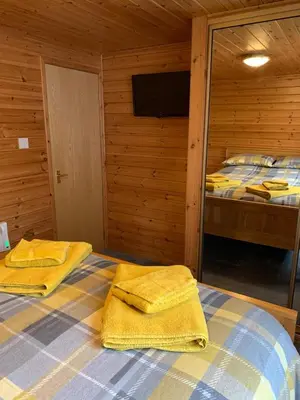 a bedroom with two beds and yellow towels on a bed at Corrie Lodge, Glendevon in Glendevon