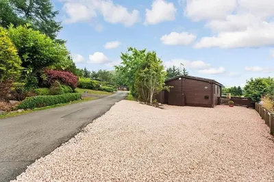 a gravel driveway with a small shed on the side of a road at Corrie Lodge, Glendevon in Glendevon