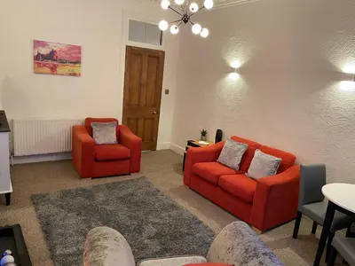 a living room with two red chairs and a table at Heart of George street / Oban / Argyll in Oban