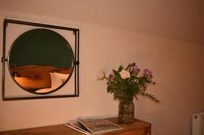 a vase of flowers on a table with a mirror at Orchy Bank House in Dalmally