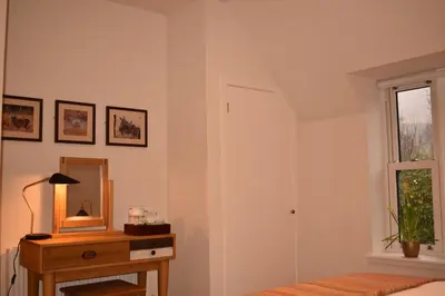 a bedroom with a bed and a mirror and a table at Orchy Bank House in Dalmally