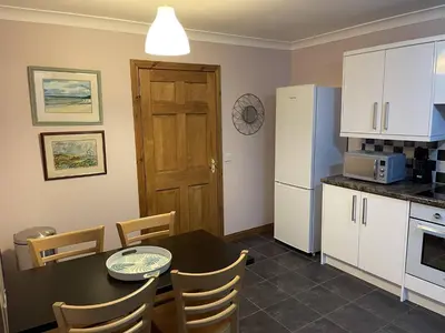 a kitchen with a table and a refrigerator at Foxglove Cottages in Drymen