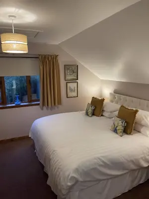 a large white bed in a room with a window at Foxglove Cottages in Drymen