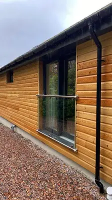 a cabin with a balcony on the side of it at The Heronry Hideaway with luxury hot tub in Ballachulish