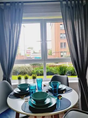 a table with plates and glasses on it in front of a window at Stylish 2 bedroom Apartment / FREE Gated Parking in Glasgow