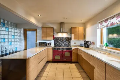 a kitchen with wooden cabinets and a red stove at Tanamuir, overlooking Loch Fyne, Strachur in Cairndow