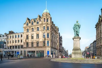 a statue in the middle of a street in front of a building at RÌGH Residences - George Street in Edinburgh