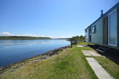 a train is parked next to a river at Sunnybrae, Isle of Luing in Cullipool