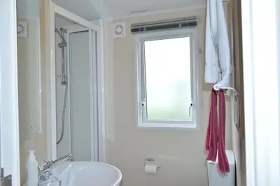 a white bathroom with a sink and a window at Sunnybrae, Isle of Luing in Cullipool