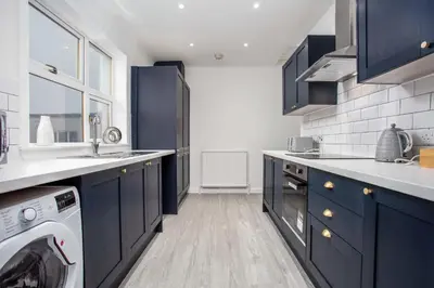 a kitchen with blue cabinets and a washing machine at Wellington View - Donnini Apartments in Ayr