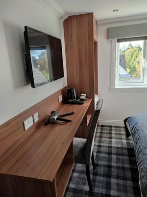 a desk in a hotel room with a bed and a television at Mango the Hotel in Haggs
