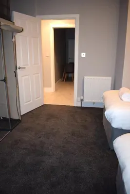 a room with two beds and an open door at Kelpies Serviced Apartments- Robertson in Falkirk
