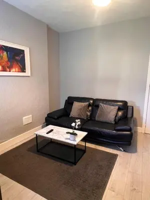 a living room with a black couch and a coffee table at Kelpies Serviced Apartments- Robertson in Falkirk