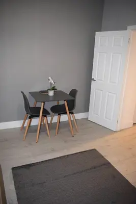 a table and chairs in a room with a door at Kelpies Serviced Apartments- Robertson in Falkirk