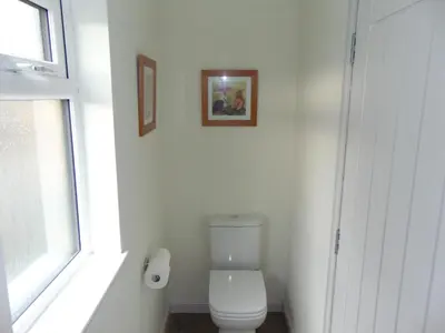 a bathroom with a toilet with two pictures on the wall at Dreamwood Cottage, Loch Lomond, Luxury Apartment. in Glasgow