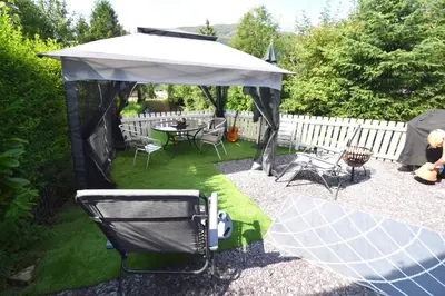 a gazebo with a table and chairs in a yard at Hollybank Cottage in Lochgoilhead