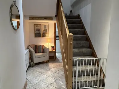 a hallway with a staircase with a couch and a chair at Hollybank Cottage in Lochgoilhead
