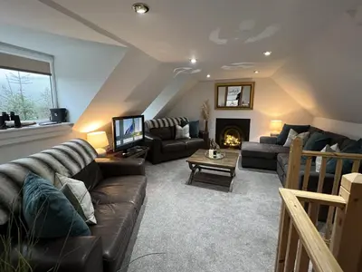 a living room with a couch and a fireplace at Hollybank Cottage in Lochgoilhead