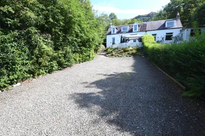 a gravel road in front of a house at Hollybank Cottage in Lochgoilhead