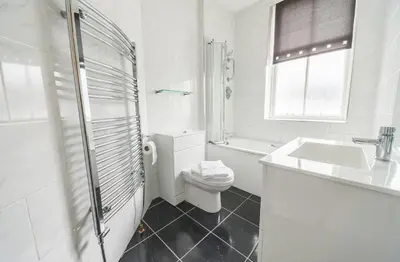 a white bathroom with a toilet and a sink at SGE Esplanade Hotel in Dunoon