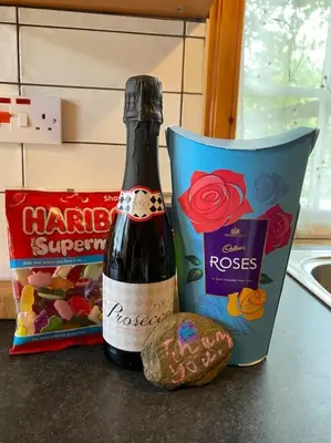 a bottle of wine and a bag of cookies on a counter at Pine Cabin, Strathyre. A cosy escape from it all. in Strathyre