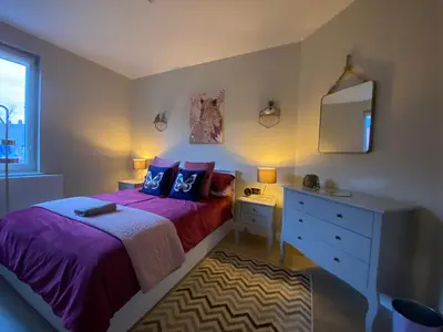 a bedroom with a bed and a dresser and a mirror at Lovely 3 bed with jacuzzi, close to airport, driveway, wifi in Edinburgh