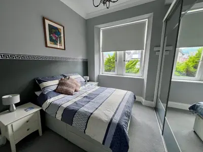 a bedroom with a bed and two windows at Seaview one bedroom apartment in centre of Largs in Largs