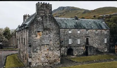 an old stone building with a mountain in the background at Menstrie Castle Stay in Stirling