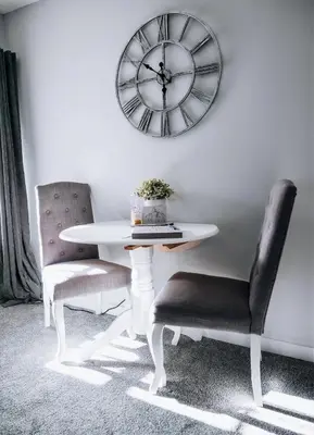 a table and two chairs and a clock on a wall at Menstrie Castle Stay in Stirling