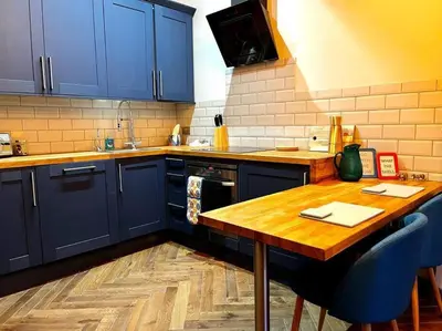 a kitchen with blue cabinets and a wooden table at Stunning 1 bed Apt in West End in Glasgow
