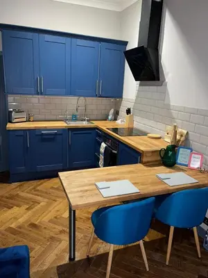 a kitchen with blue cabinets and a wooden table and chairs at Stunning 1 bed Apt in West End in Glasgow