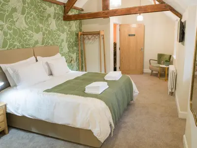 a bedroom with a large bed with a green blanket at Coach House Ratho Park Steading in Ratho