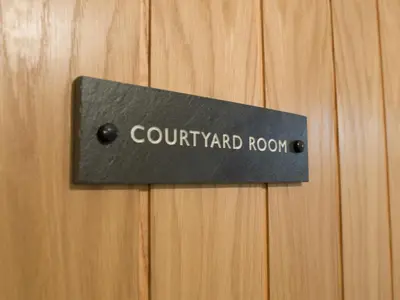 a sign on a wooden door with the words cour yard room at Coach House Ratho Park Steading in Ratho