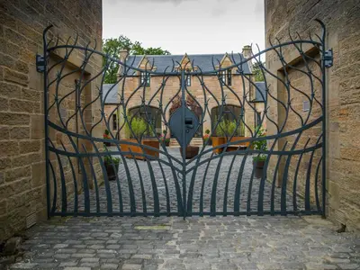 an open gate to a building with potted plants at Coach House Ratho Park Steading in Ratho